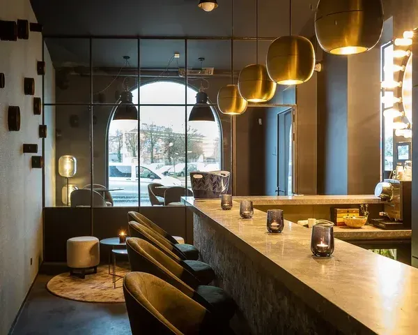 Moderne kantoorruimte met gouden hanglampen, houten balie, grote ramen en stijlvolle inrichting in warme tinten