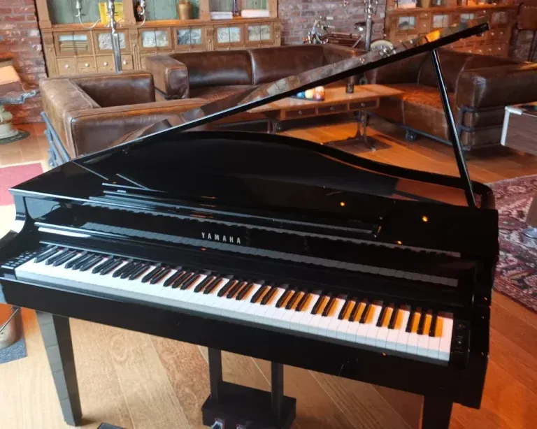 Zwarte Yamaha vleugelpiano met open klep in elegant interieur met lederen zithoeken en houten afwerking